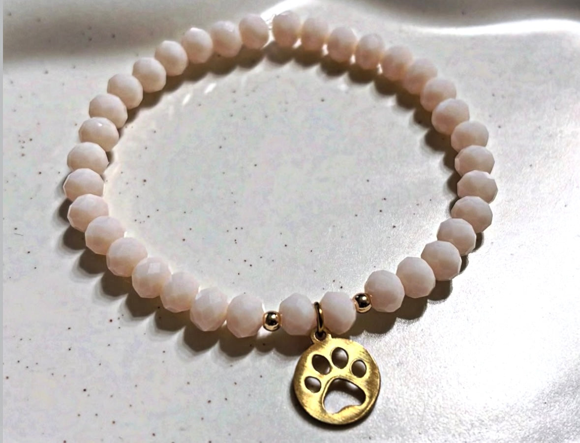 Bracelet made of shimmering pearls with golden paw print charms