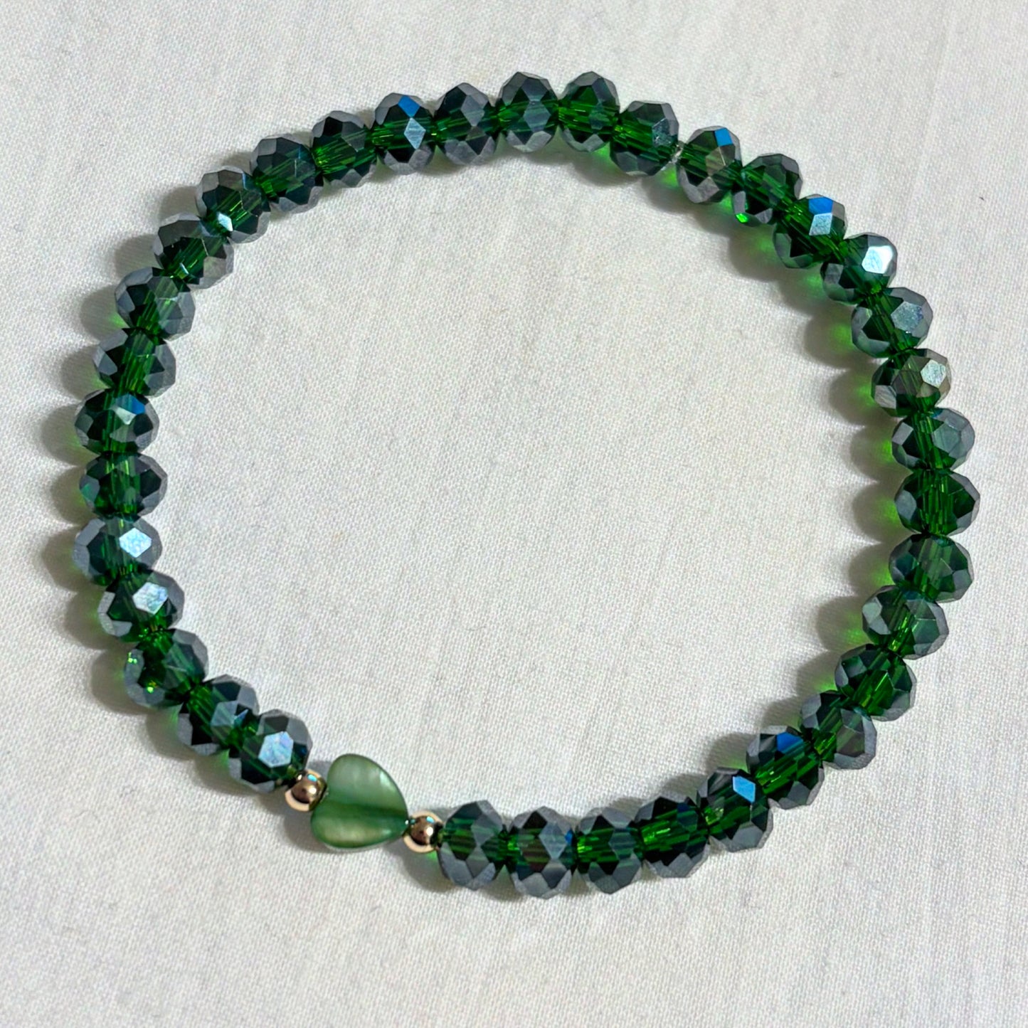 Armband grün mit herzförmiger Muschelperle und goldenen Details